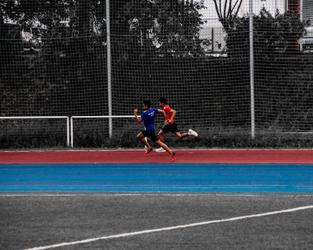 An athlete sprinting outdoors with a coach observing and timing the run.