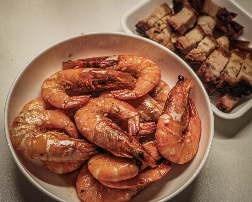 a bowl of shrimp next to a bowl of meat