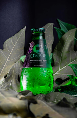 A vibrant display of Awshal Water bottles in 250 ml, 500 ml, and 1500 ml sizes, each featuring the signature pink label against a backdrop of fresh mountain springs.