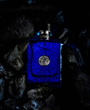 A minimalist bottle of ixq spirit set against a deep indigo background with flowing wave patterns.