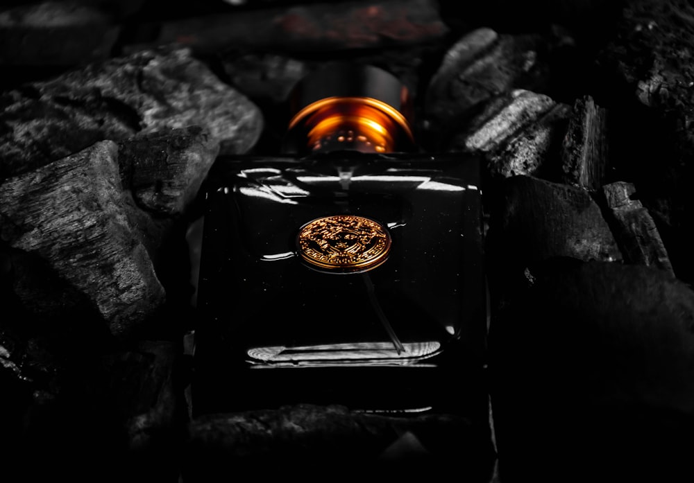 a bottle of perfume sitting on top of a pile of rocks