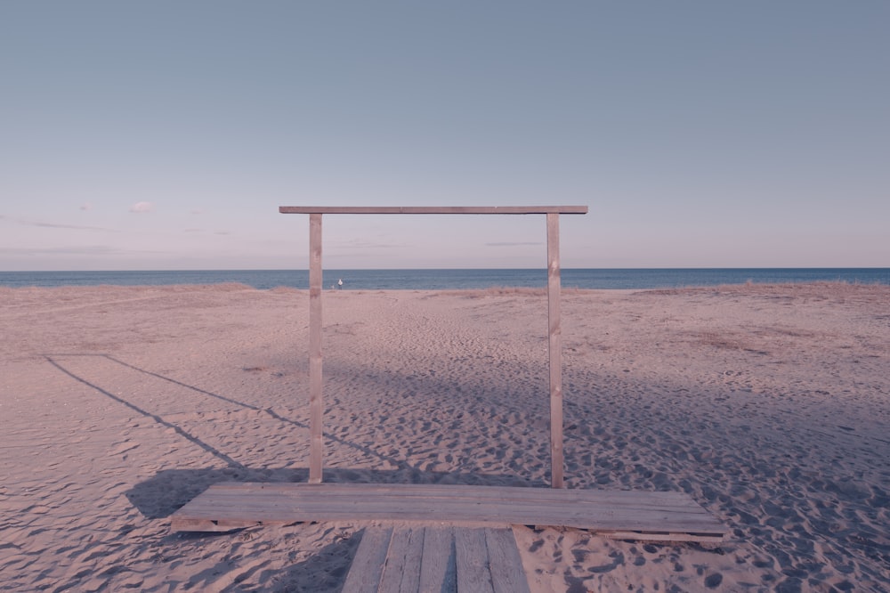 a wooden bench sitting on top of a sandy beach
