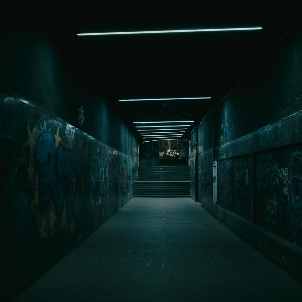 a dark hallway with graffiti on the walls