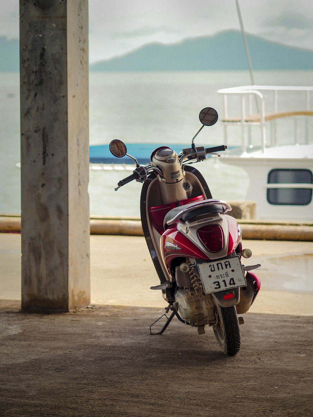 a red and white motorcycle parked next to a boat