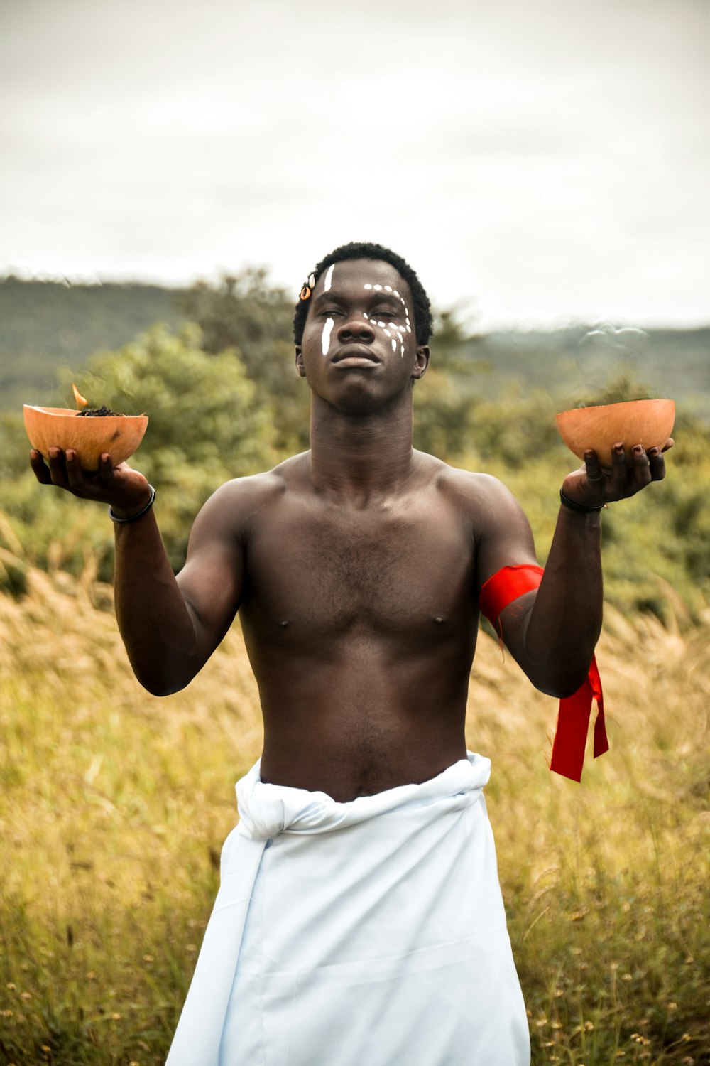 a man with no shirt holding two pieces of fruit