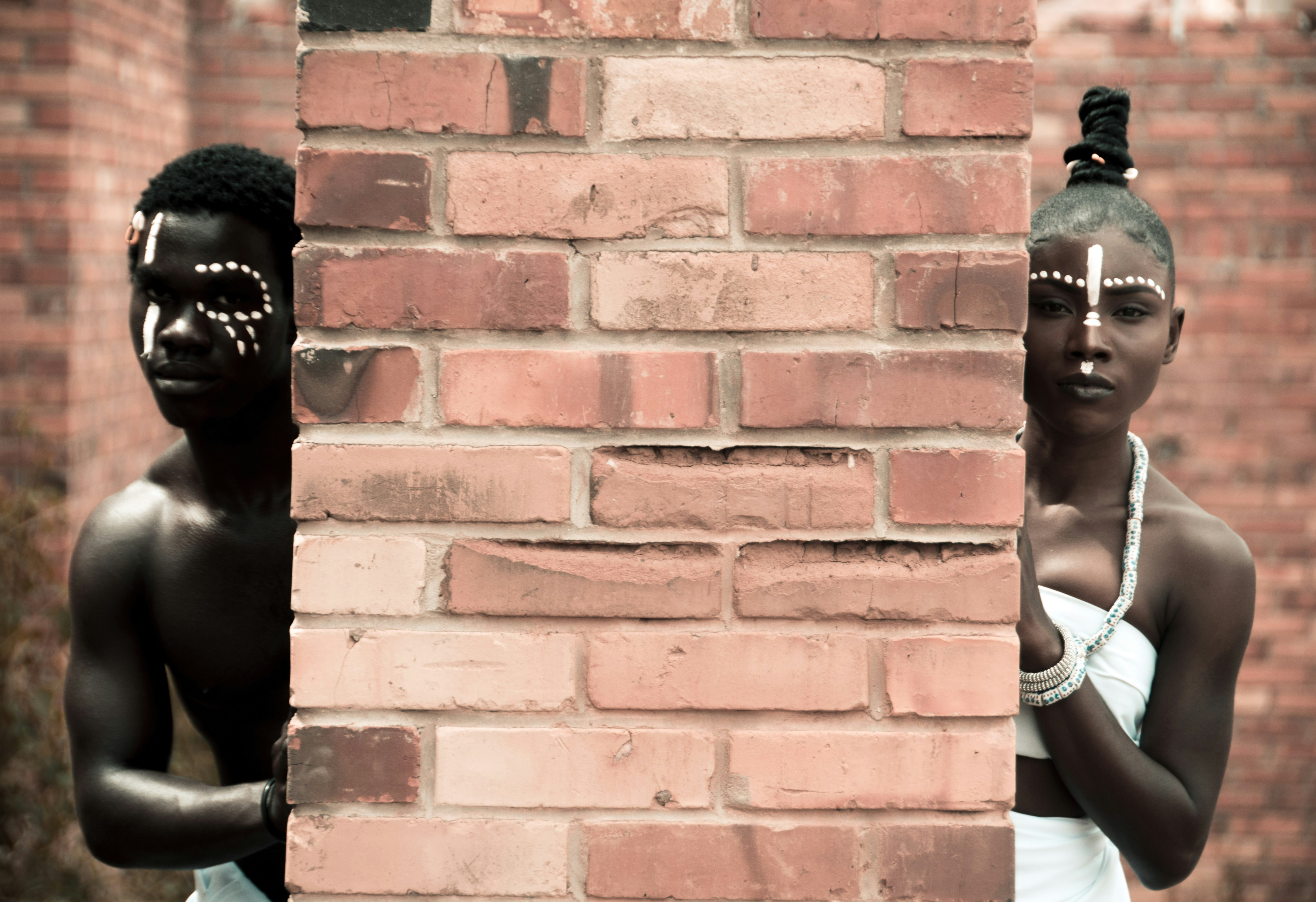 a couple of people standing next to a brick wall