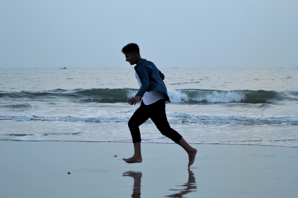 a man walking along a beach next to the ocean