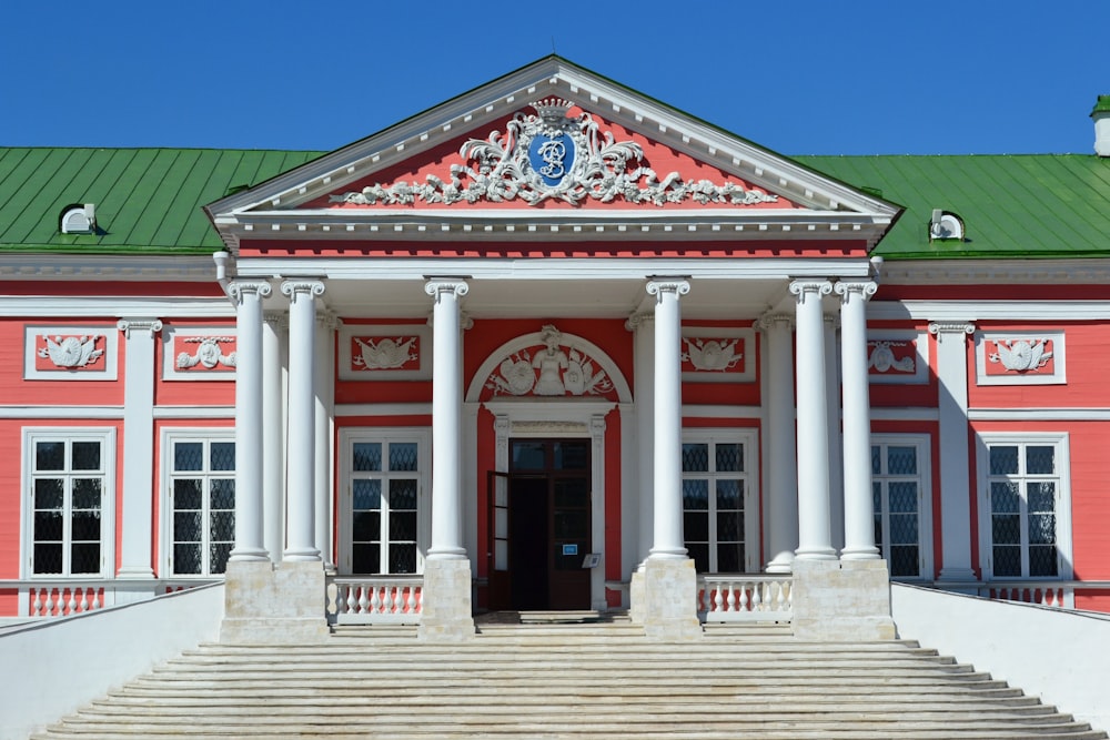 a red building with a green roof and white columns