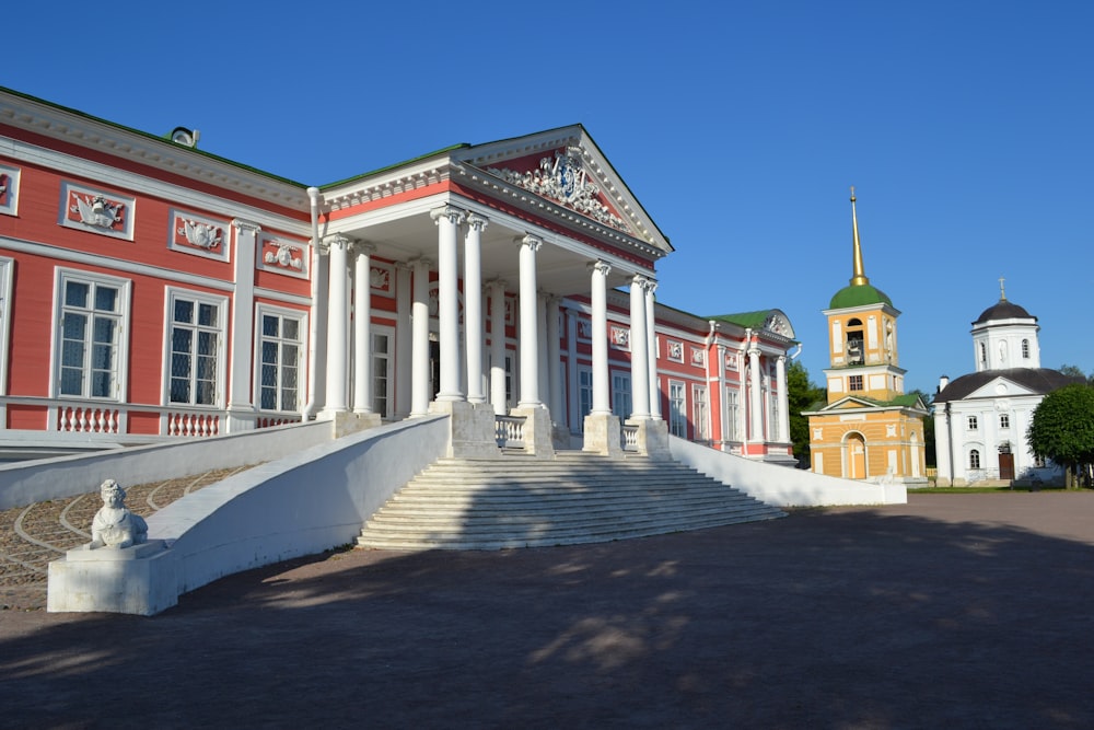 a red and white building with columns and a clock tower