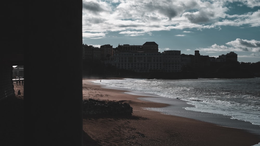a black and white photo of a beach with buildings in the background
