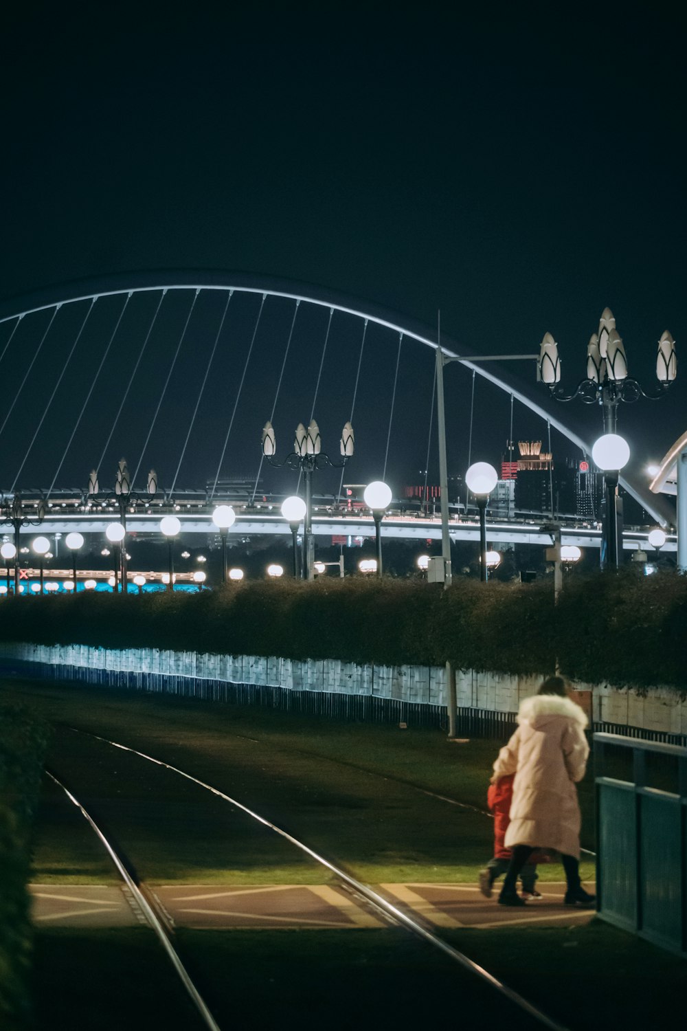 a couple of people walking down a train track at night