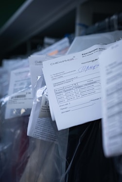 Several documents with Cyrillic text are visible, placed in a stack with clear plastic packaging around them. The focus is on a receipt or invoice in Russian, featuring printed and handwritten text.