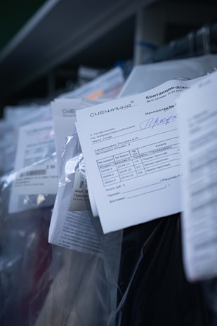 Several documents with Cyrillic text are visible, placed in a stack with clear plastic packaging around them. The focus is on a receipt or invoice in Russian, featuring printed and handwritten text.