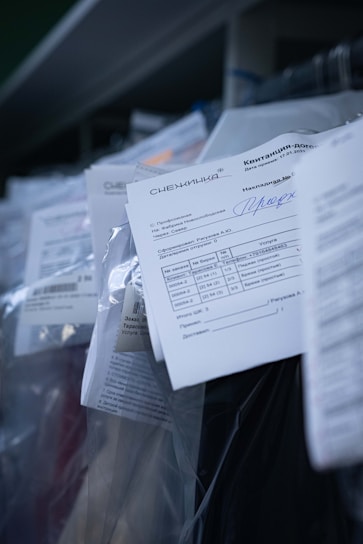 Several documents with Cyrillic text are visible, placed in a stack with clear plastic packaging around them. The focus is on a receipt or invoice in Russian, featuring printed and handwritten text.