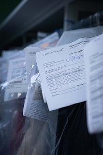 Several documents with Cyrillic text are visible, placed in a stack with clear plastic packaging around them. The focus is on a receipt or invoice in Russian, featuring printed and handwritten text.
