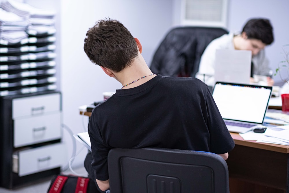 a man sitting at a desk in front of a laptop computer