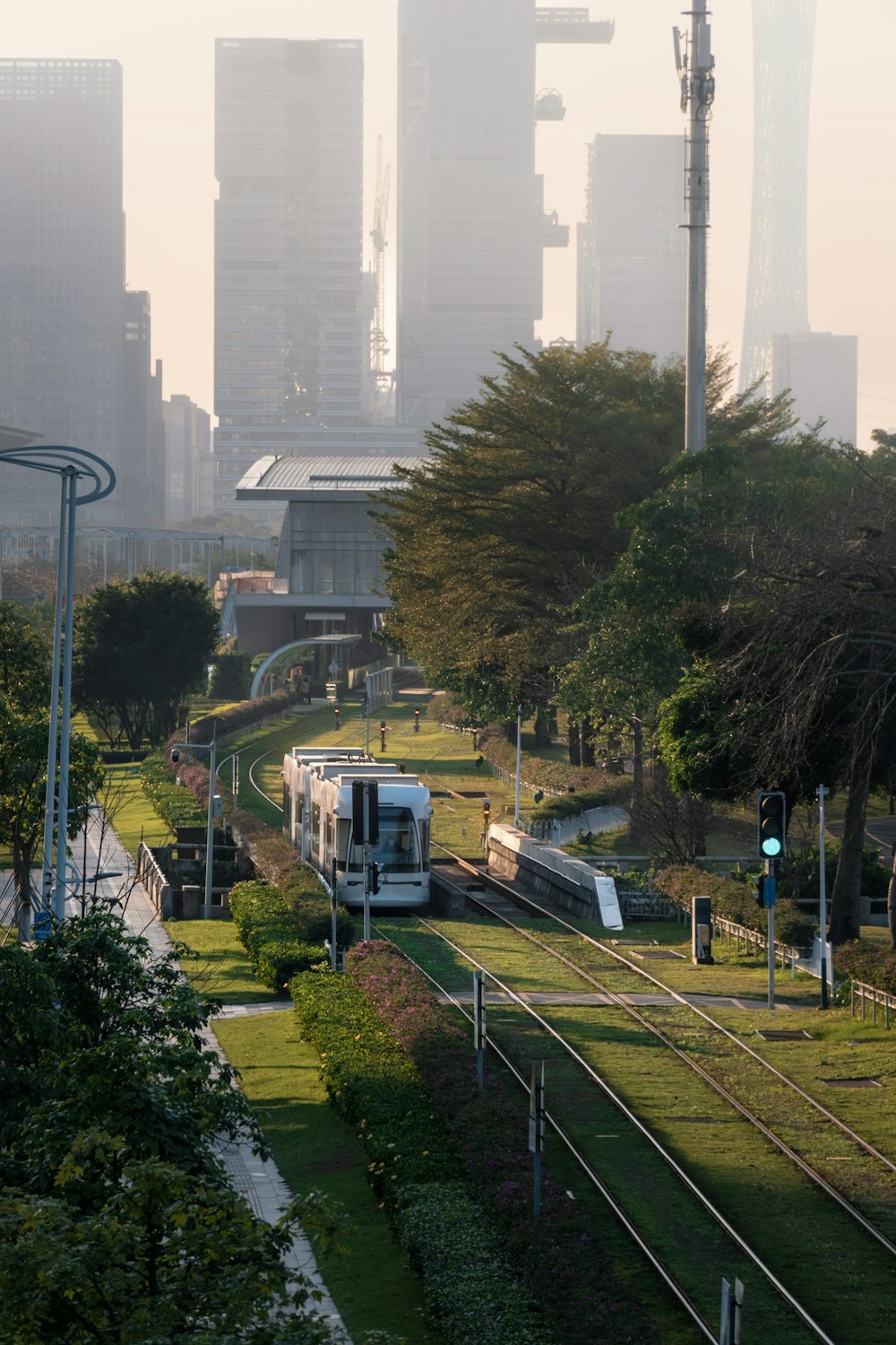 a train traveling down train tracks next to a lush green park