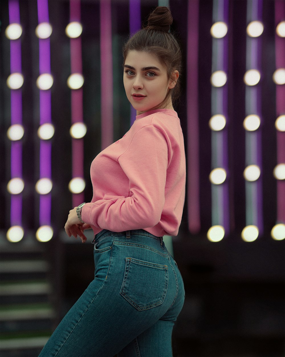 a woman in a pink sweater and jeans posing for a picture
