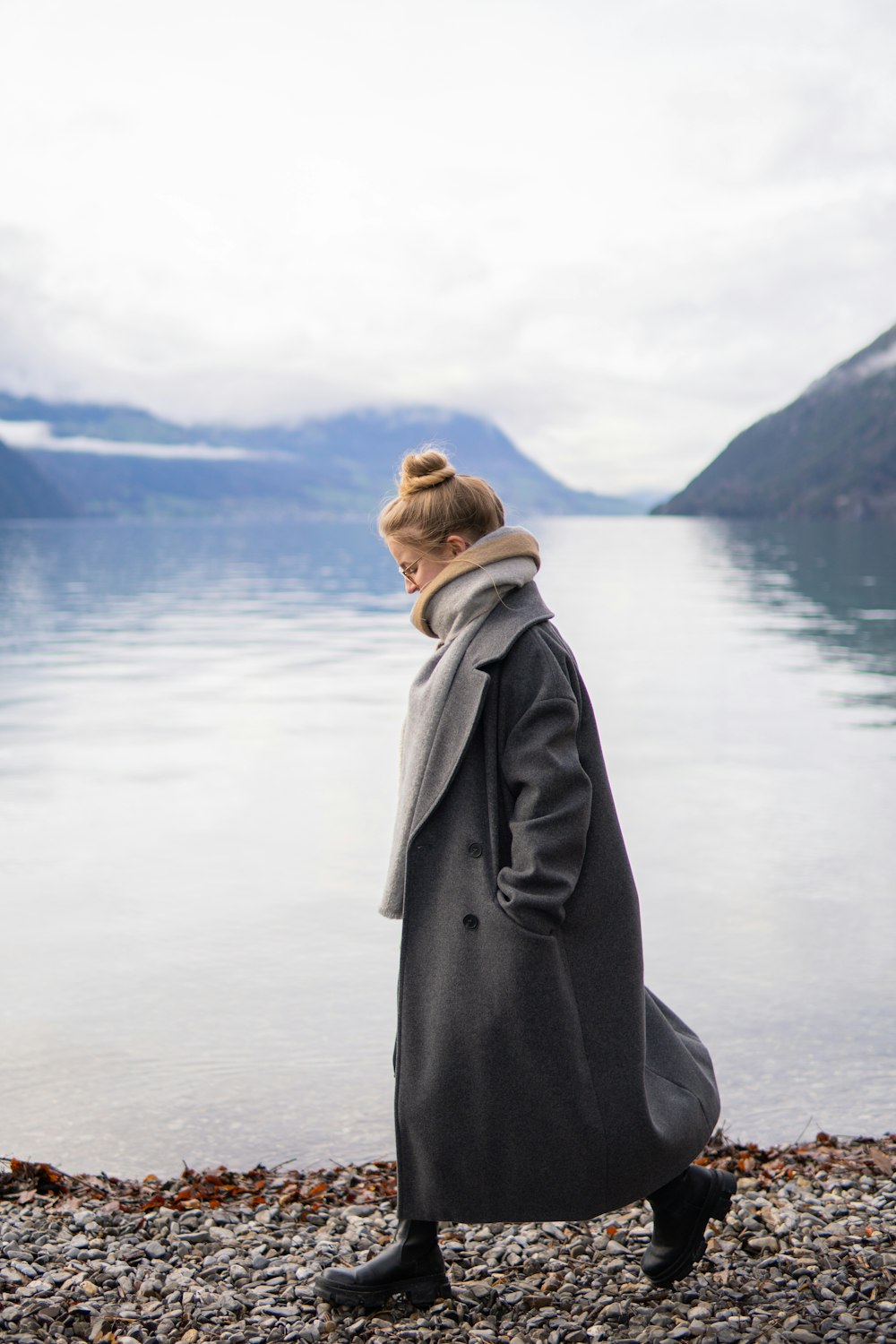 a woman walking on a rocky beach next to a body of water