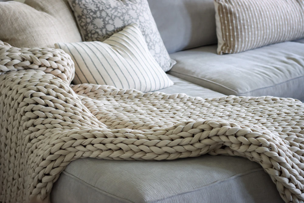 Cream chunky knit throw blanket draped over a sofa