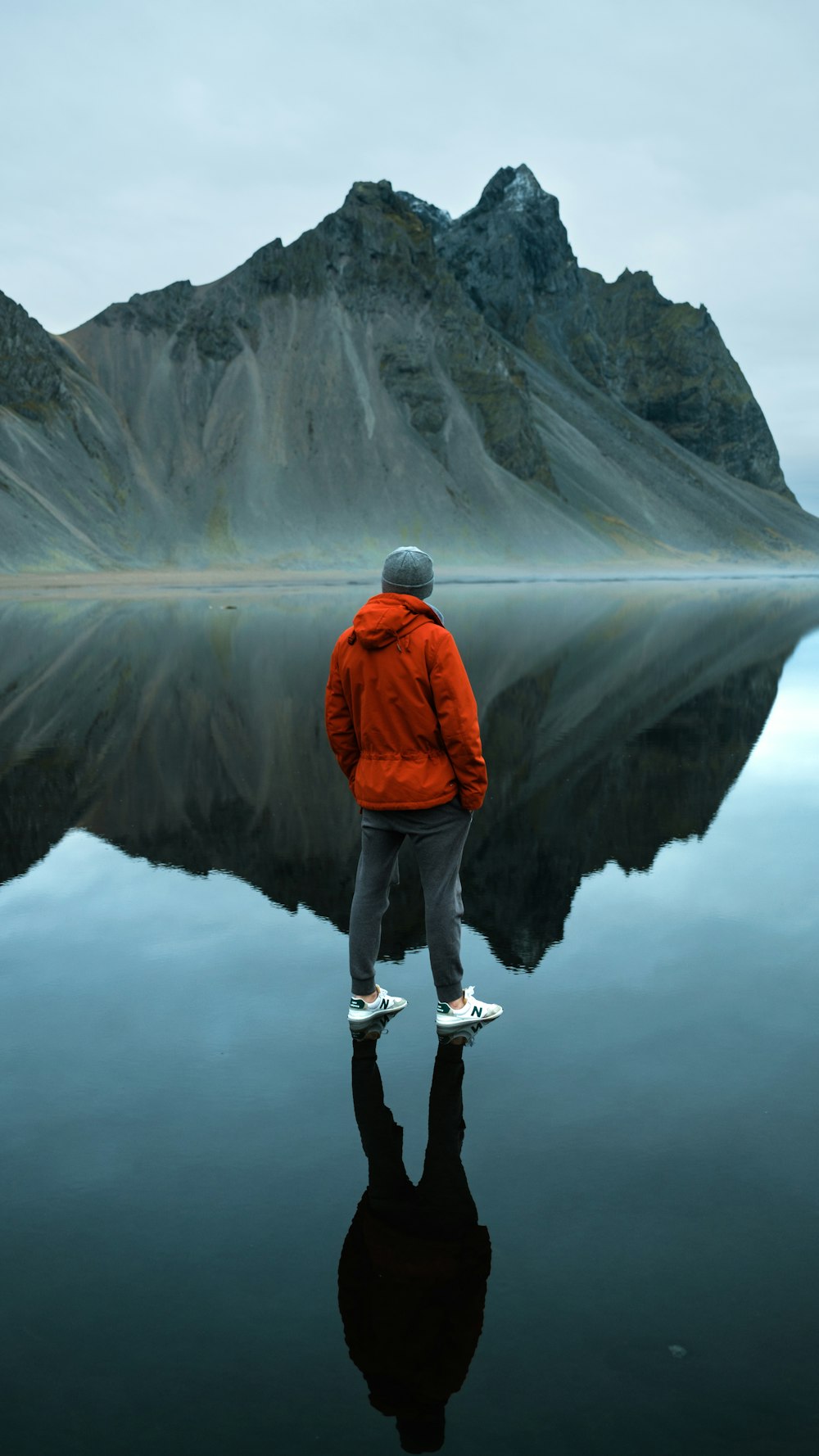 a man in a red jacket is standing in front of a mountain