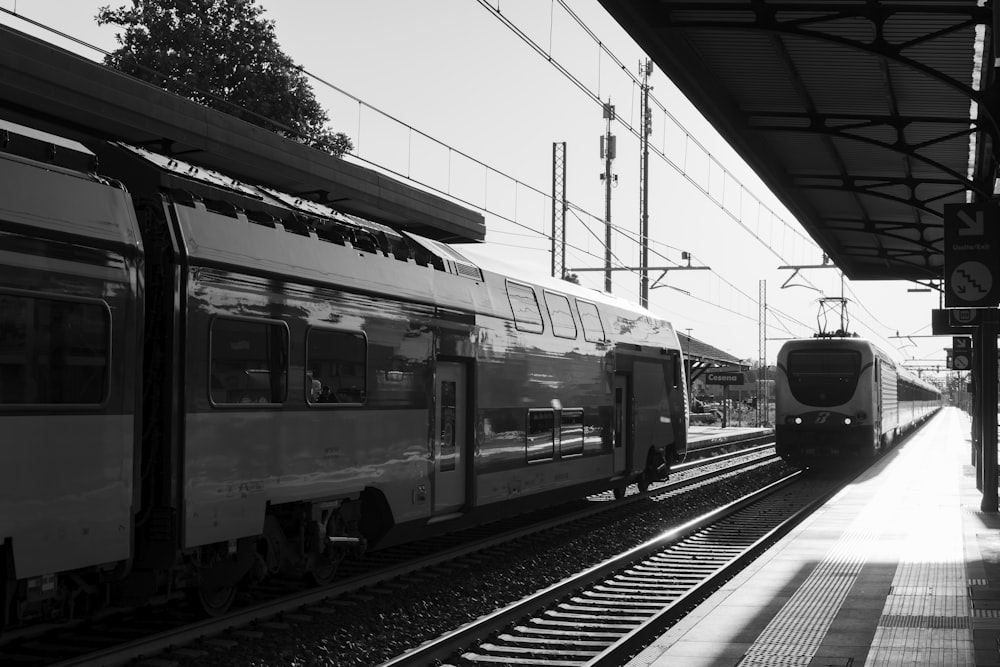 Una foto in bianco e nero di due treni in una stazione ferroviaria