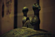 Close-up of a bronze frying pan with a warm patina, set against a backdrop of ancient bronze patterns.