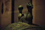 Close-up of a bronze frying pan with a warm patina, set against a backdrop of ancient bronze patterns.