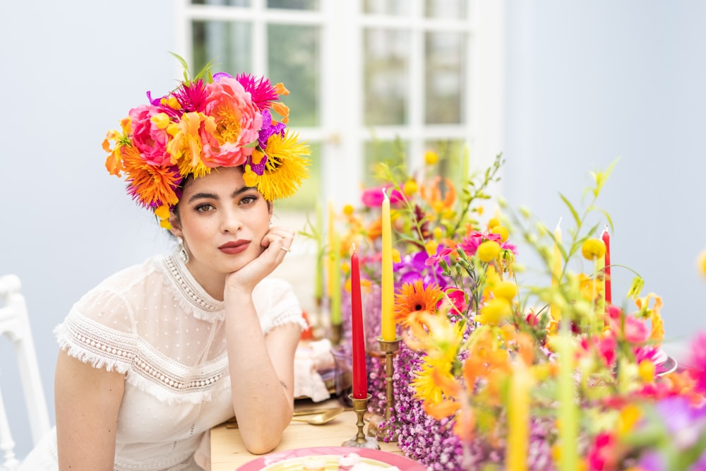 a woman sitting at a table with flowers in her hair