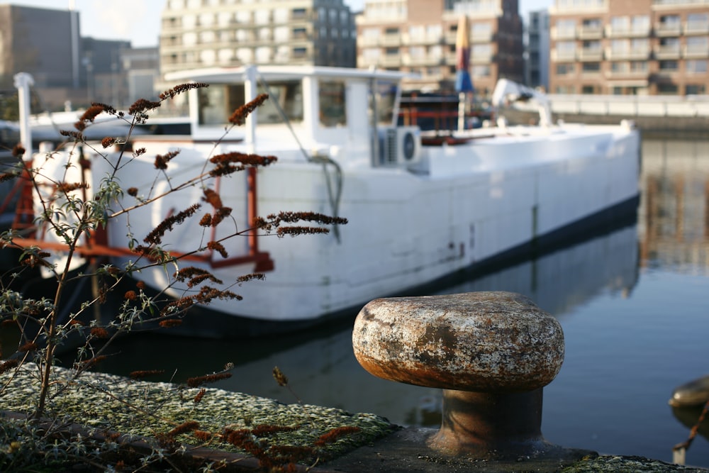 a white boat docked in a harbor next to tall buildings