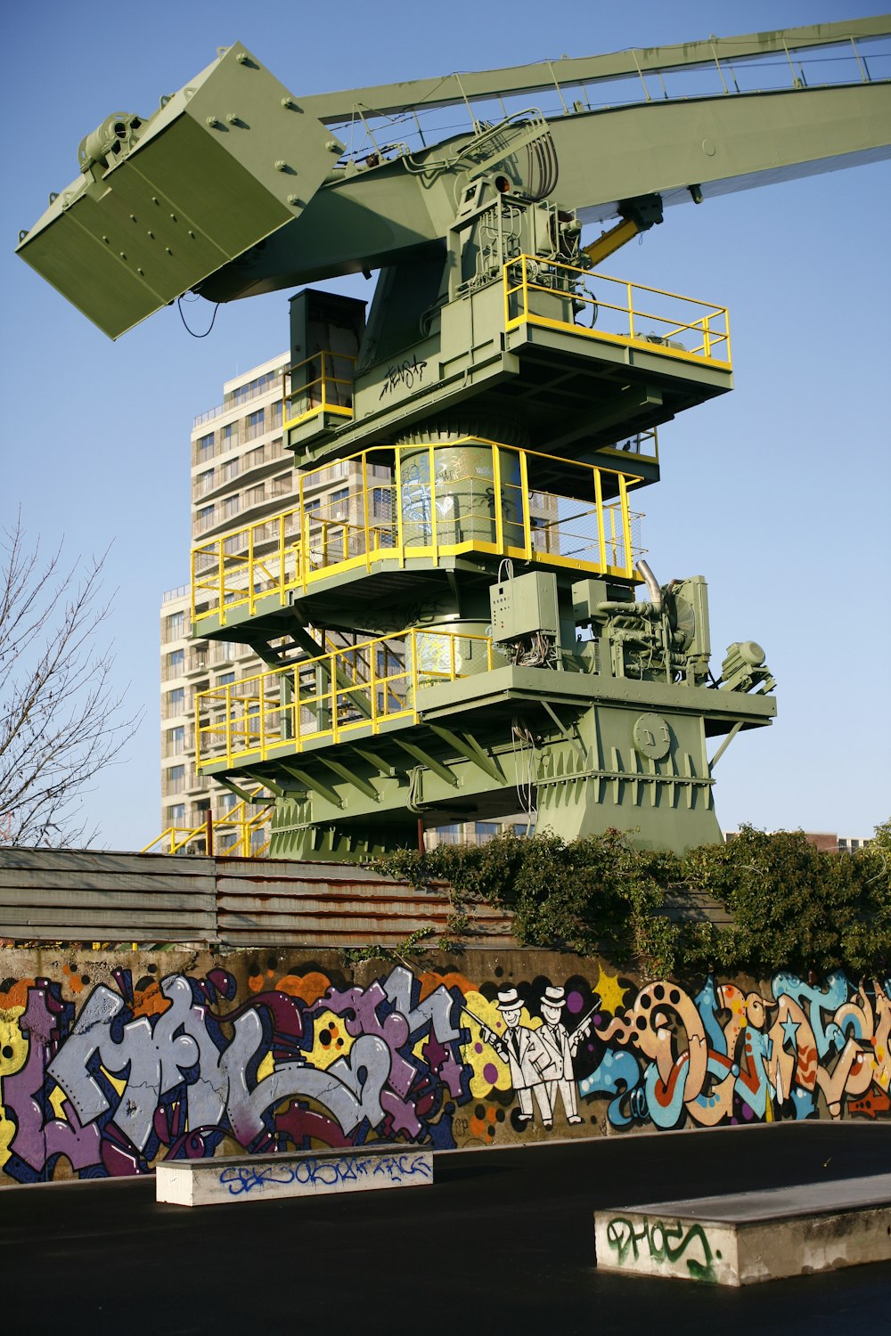 a large crane sitting next to a building with graffiti on it