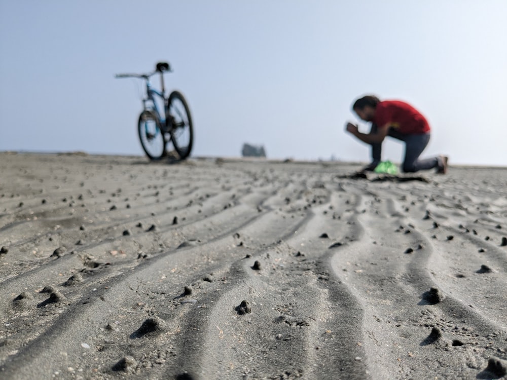 a man kneeling down on top of a sandy beach