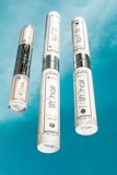 Three bottles of beauty products with silver accents are arranged on a bright blue background. The labels read 'lift hair' with various product names including shampoo and soin. The overall design is clean and modern.