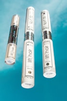 Three bottles of beauty products with silver accents are arranged on a bright blue background. The labels read 'lift hair' with various product names including shampoo and soin. The overall design is clean and modern.