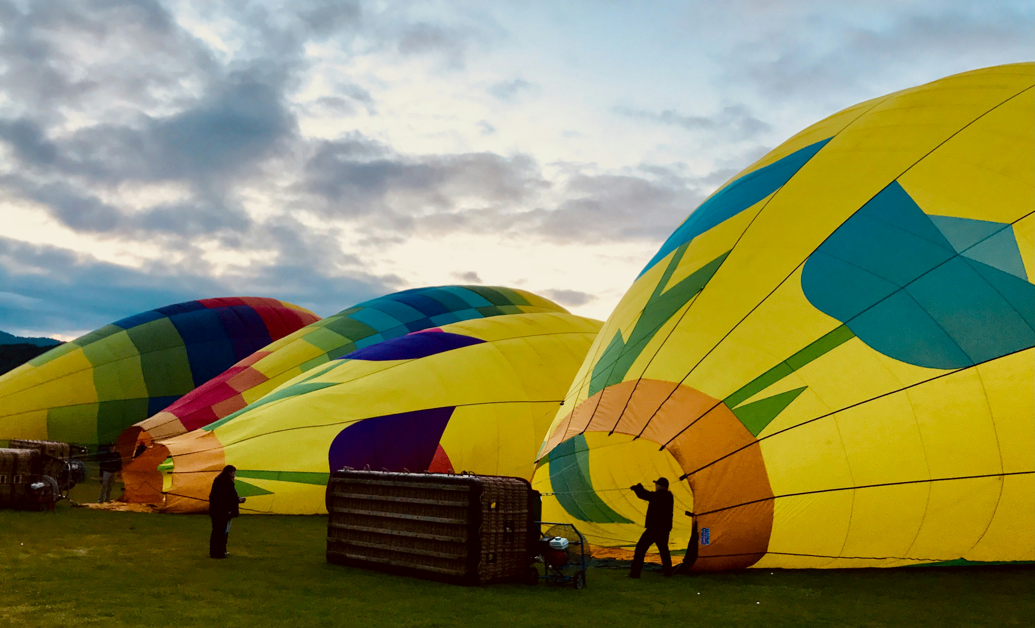 a group of people working on a large balloon, Hot air balloons being prepared for flight