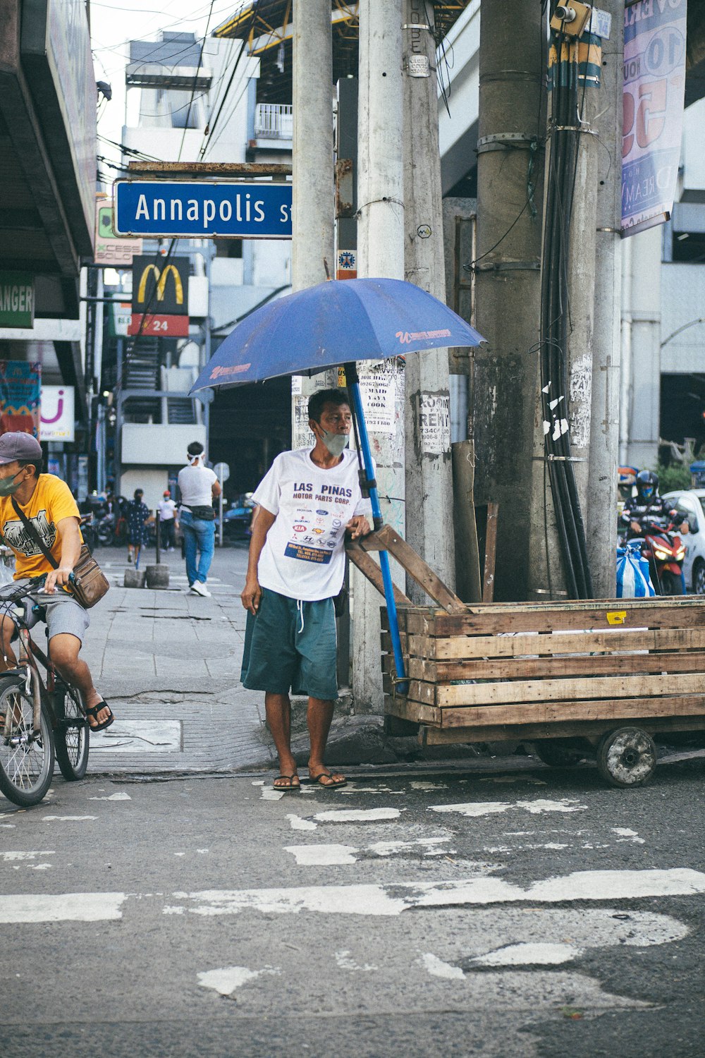 um homem andando por uma rua segurando um guarda-chuva azul