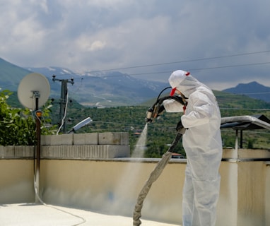 a man in a white suit spraying foam on a roof