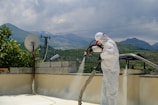 a man in a white suit spraying water on a roof