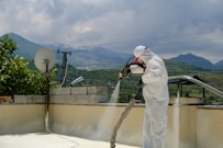 a man in a white suit spraying water on a roof