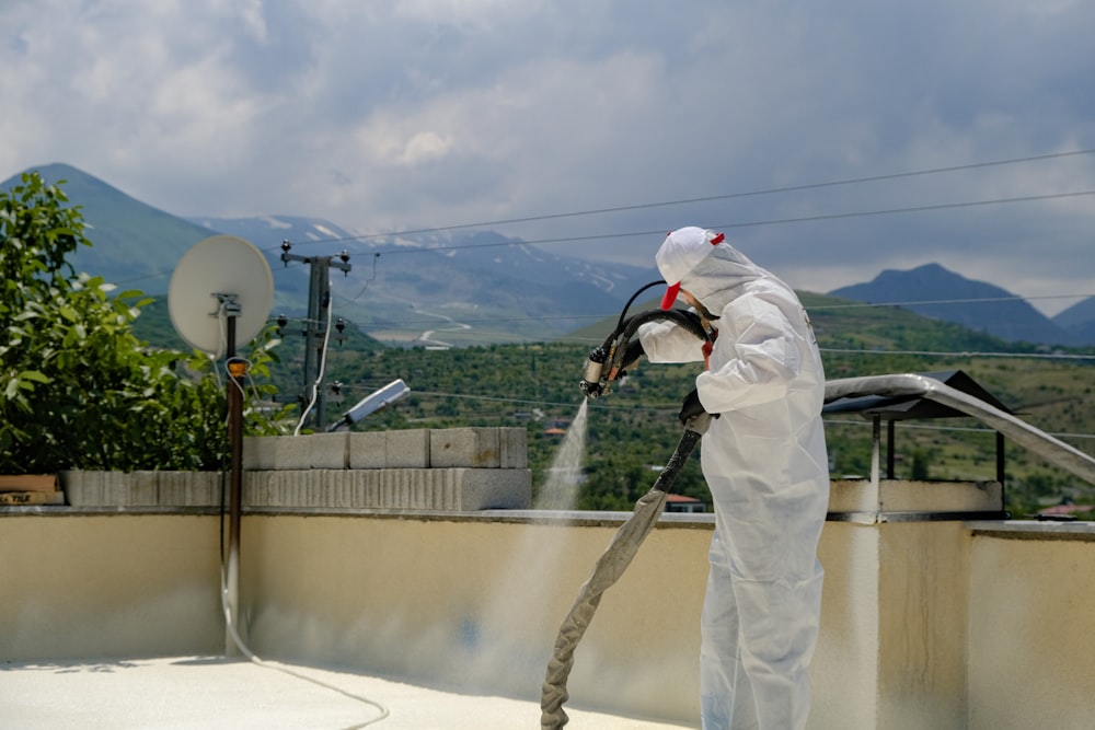a man in a white suit spraying water on a roof