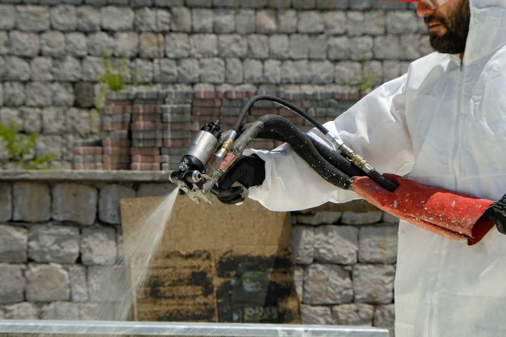 a man in a white coverall spraying water with a hose