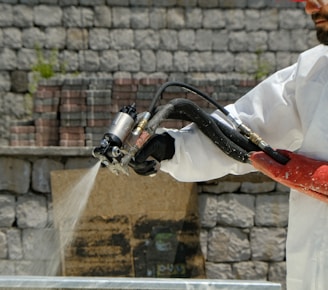 a man in a white coverall spraying water with a hose