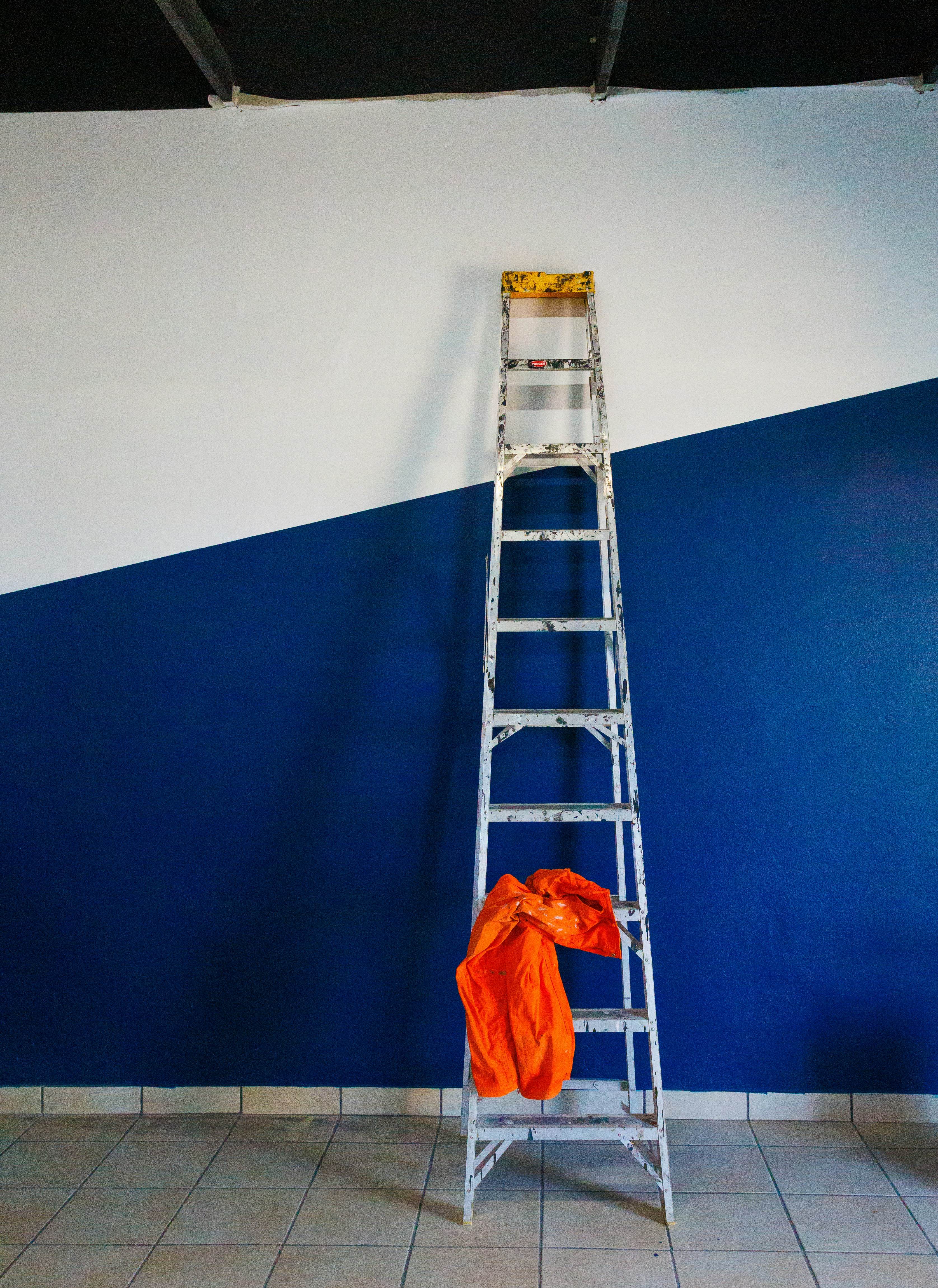 una escalera apoyada contra una pared azul y blanca
