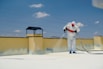 a man in a white coverall spray painting a roof