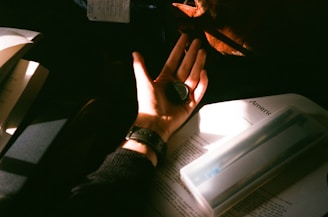 Close-up of hands gently holding a colorful sticker-book journal, sunlight casting soft shadows.