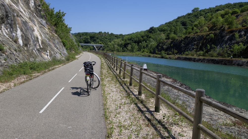 a bicycle parked on the side of a road next to a river