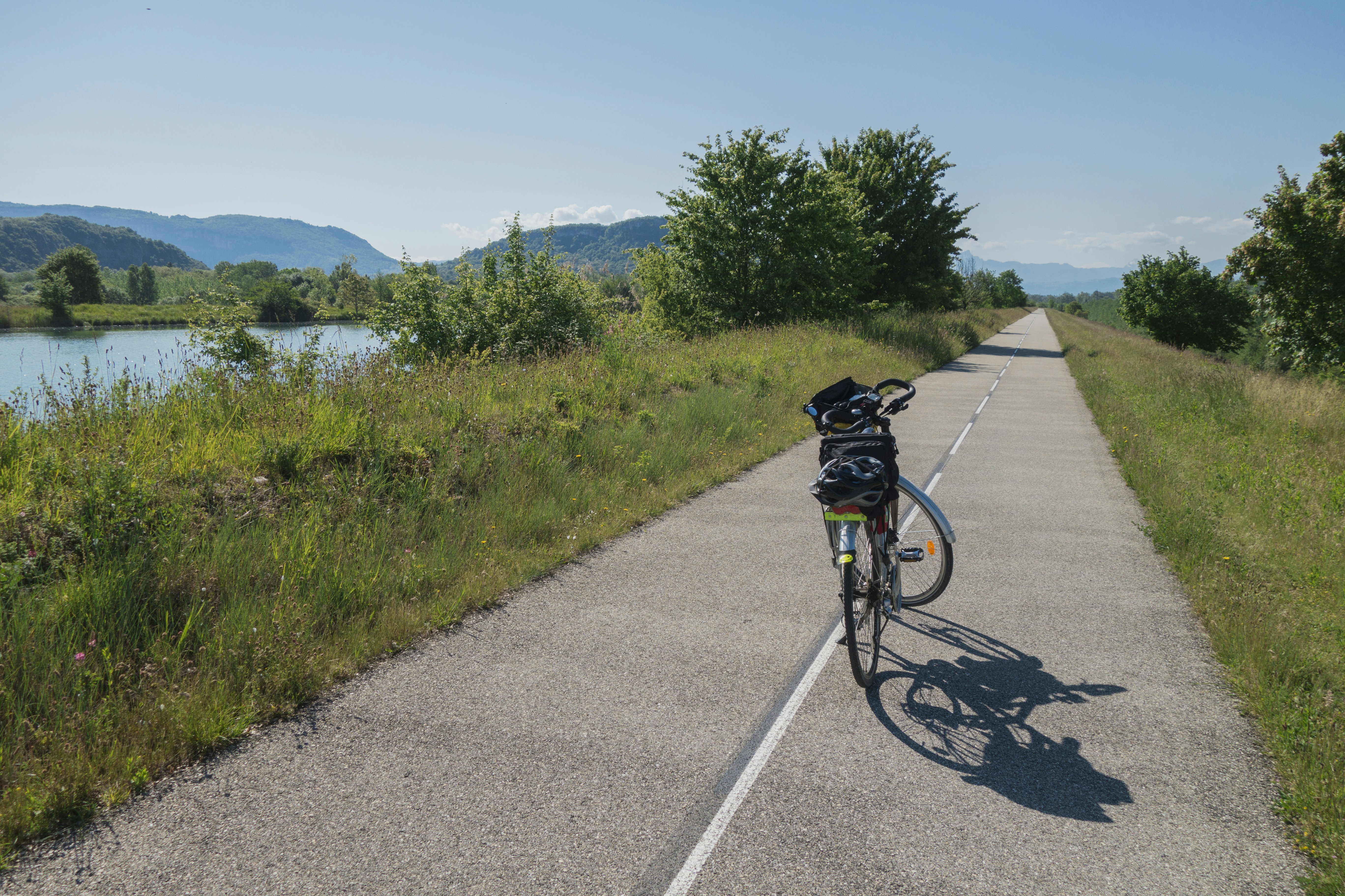 a bicycle parked on the side of a road next to a lake