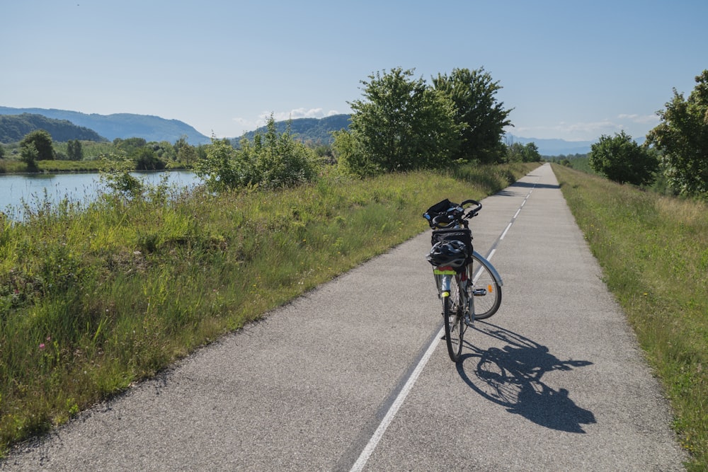 a bicycle parked on the side of a road next to a lake