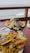 A smiling woman enjoying a colorful Caribbean seafood dish at a seaside table with teal accents.
