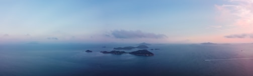 A panoramic view of the sea with small islands scattered, as seen from the boat during a sunny afternoon.